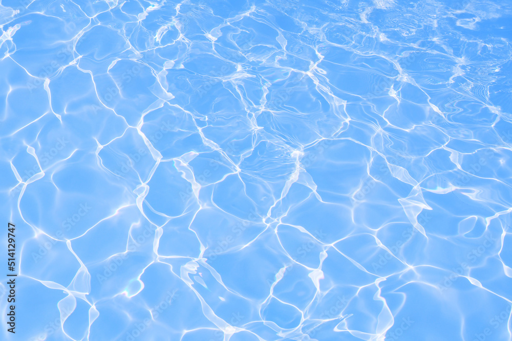 Blue water surface with bright sun light reflections, blue water in swimming pool background