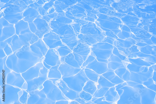 Blue water surface with bright sun light reflections, blue water in swimming pool background