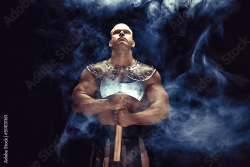 Studio shot of muscular ancient warrior man posing with axe
