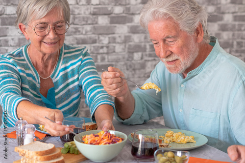 Beautiful senior couple sitting at table having brunch together at home
