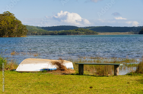 A wooden bench and a rowing boat on the shore of Smiths Lake - Tarbuck Bay, NSW, Australia photo