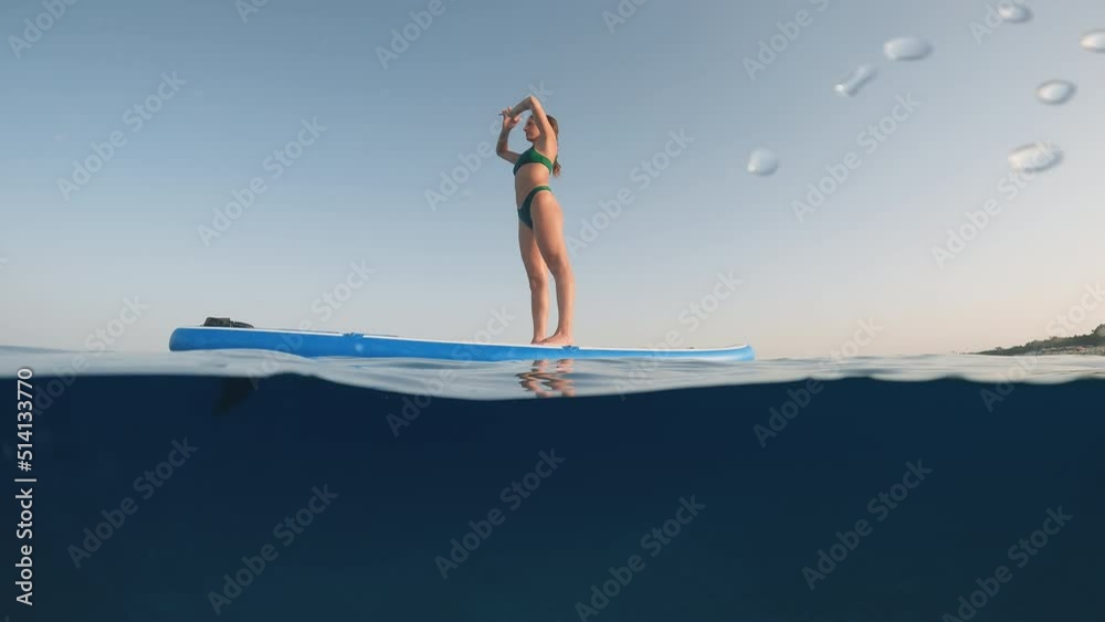 Girl does Yoga on the stand up paddle sup in Summer in the sea Girl does Yoga on the stand up paddle sup in Summer in the sea