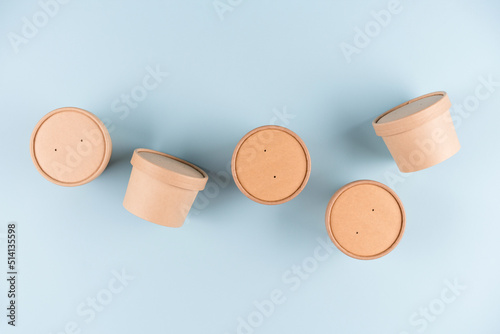 Eco kraft paper food containers for soup to go or ice cream, cup with paper cap over light blue background, mockup image. Sustainable food packaging concept. Flat lay style