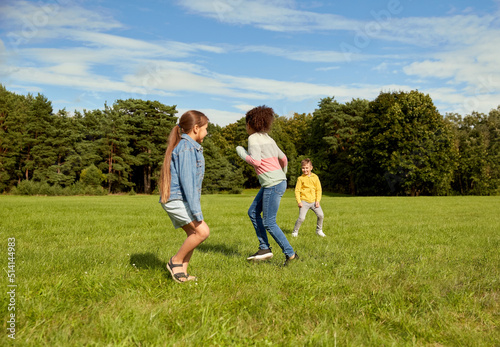 childhood, leisure and people concept - group of happy kids playing tag game and running at park