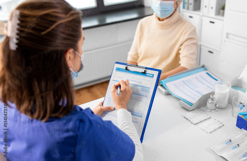 Fototapeta premium medicine, health and vaccination concept - doctor with clipboard and senior woman in mask at hospital