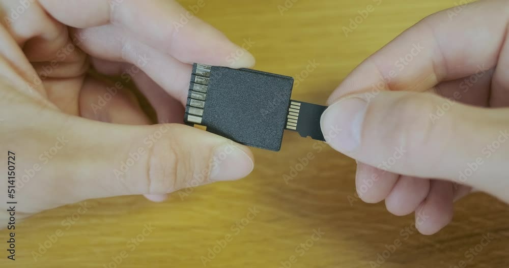 Insert micro sd memory card into sd adapter. Closeup, male hands