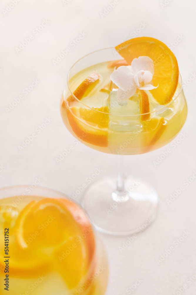 Transparent cocktail with ice cubes in a glass decorated with slices of orange close up