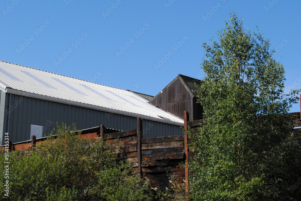 Modern Metal Industrial Buildings beside Canal against Blue Sky Modern Metal Industrial Buildings beside Canal against Blue Sky