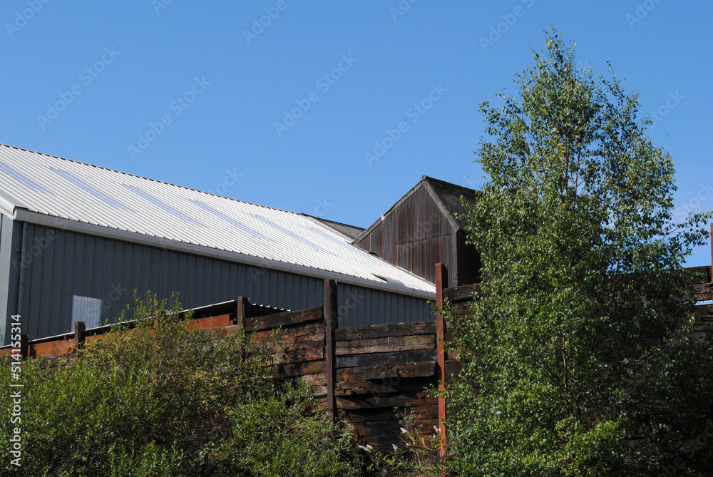 Modern Metal Industrial Buildings beside Canal against Blue Sky 