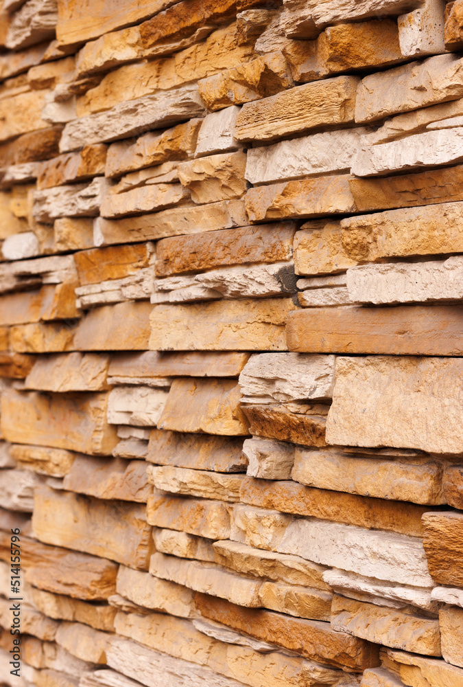 Brick wall cladding with narrow natural stones of various sizes and shapes. Angle view. Selective focus. Brick wall cladding with narrow natural stones of various sizes and shapes. Angle view. Selective focus.
