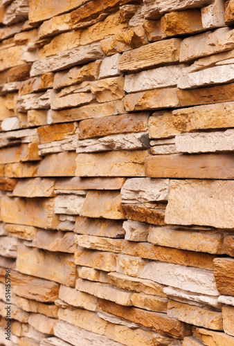Brick wall cladding with narrow natural stones of various sizes and shapes.  Angle view. Selective focus.