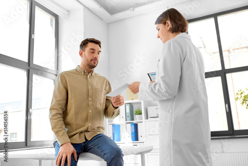 medicine, healthcare and people concept - female doctor giving prescription to man patient at hospital