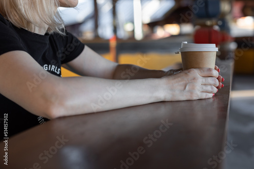 girl sitting at the counter with a paper disposable cup