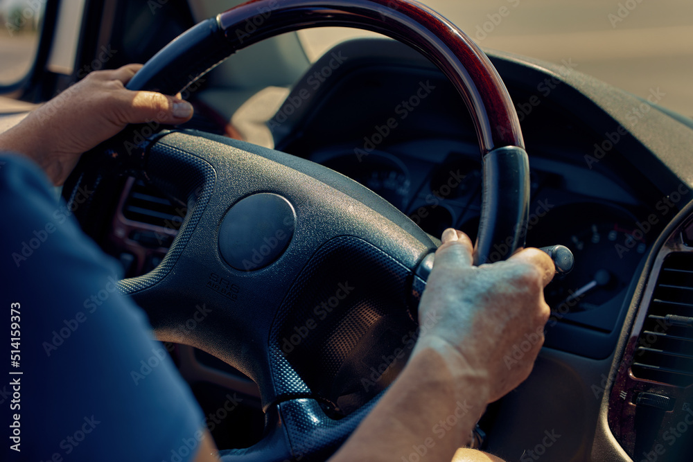 Female hands on the steering wheel of a car and the dashboard of an auto on a sunny day
