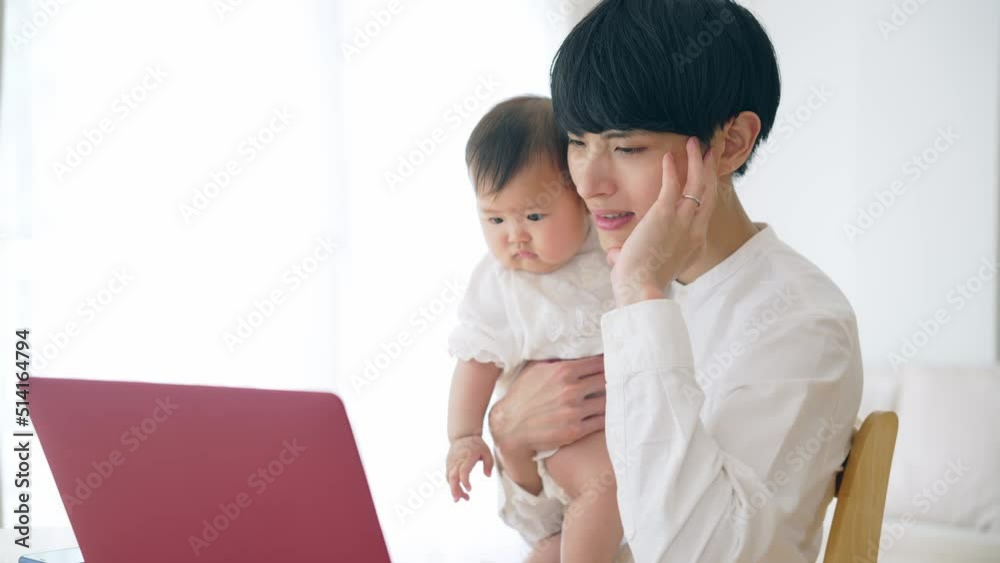 赤ちゃんを抱っこしながら自宅で仕事する男性