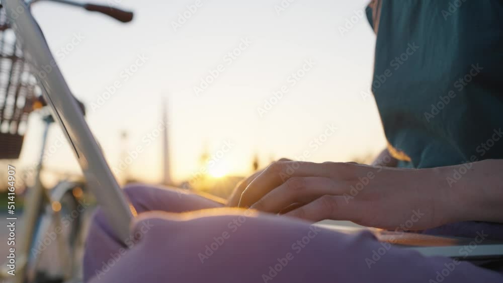 Businesswoman freelancer hands typing on a laptop keyboard at sunset in the sun in a city park in summer close-up. Woman entrepreneur working outdoors or chatting with friends online. Businesswoman freelancer hands typing on a laptop keyboard at sunset in the sun in a city park in summer close-up. Woman entrepreneur working outdoors or chatting with friends online.