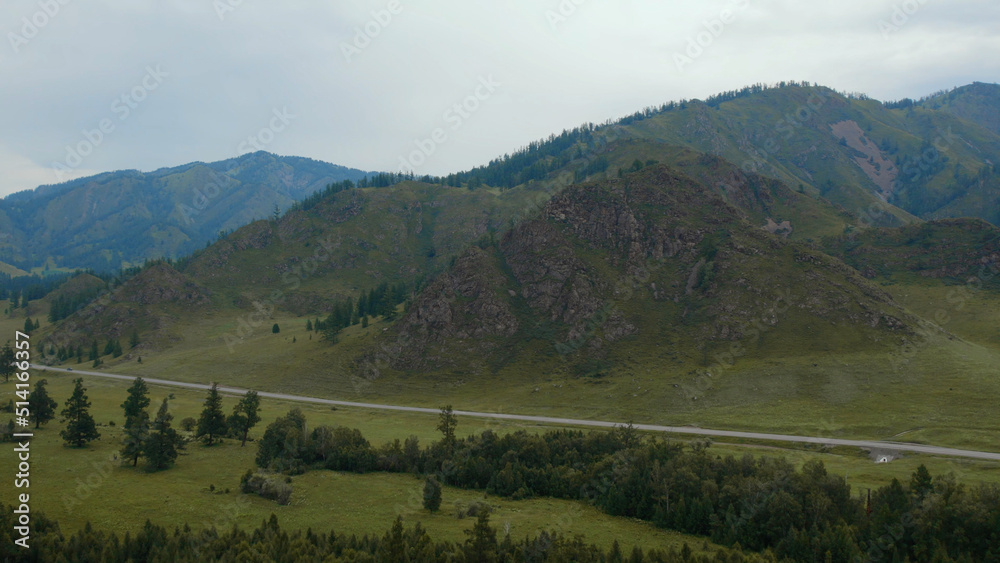 Road between field and mountains in Altai