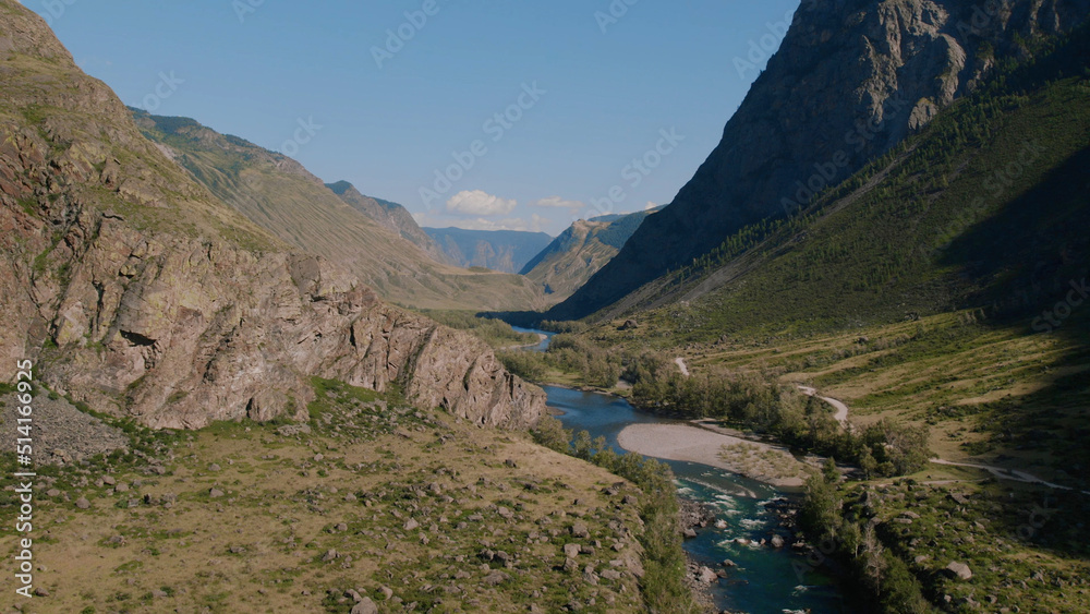 River Chulyshman between green field and mountains with blue clear sky in Altai