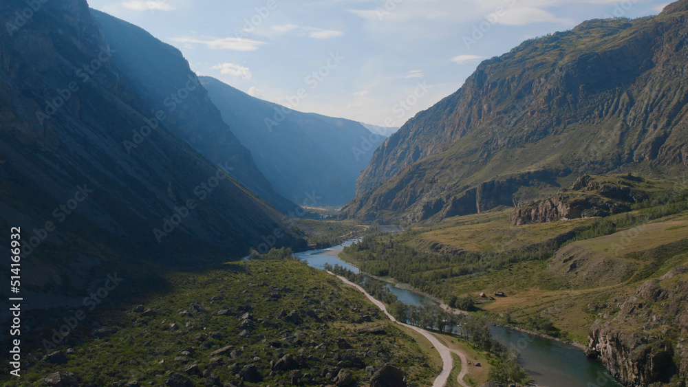 Fototapeta premium River Chulyshman between green field and mountains with blue clear sky in Altai