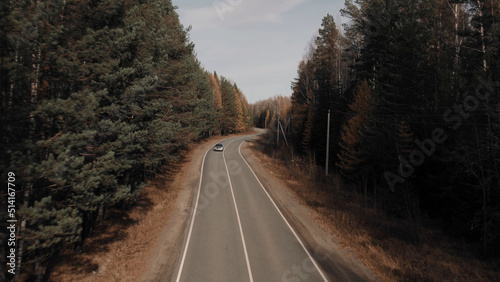 Closeup road and car between autumn forest