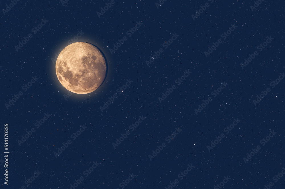 Full moon at dusk glowing against blue starry sky dark background