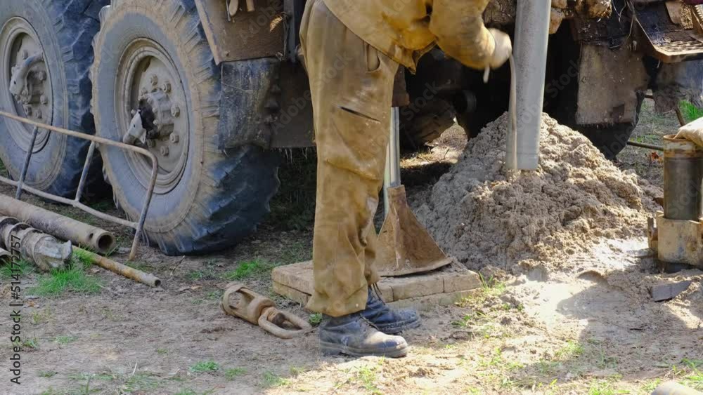 Team of workers with drilling rig on car are drilling artesian well for