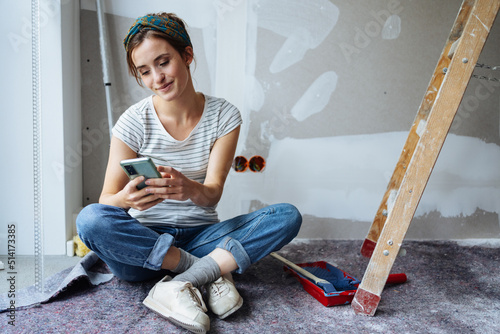 Εκτύπωση καμβά Young woman looks at her phone for ideas on how to renovate her apartment