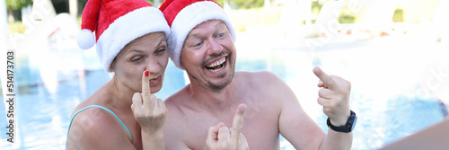 Фотография Man and woman in santa claus hats show fucking gesture into monitor