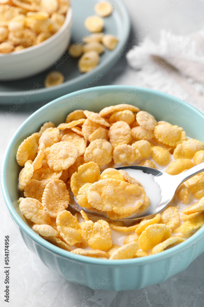 Spoon in bowl with tasty cornflakes and milk on table, closeup Spoon in bowl with tasty cornflakes and milk on table, closeup