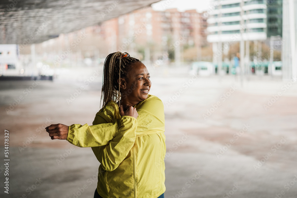 Senior african woman stretching during workout routine outdoor - Focus on face