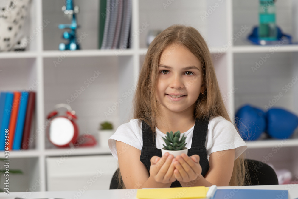 cheerful child hold potted plant in school classroom