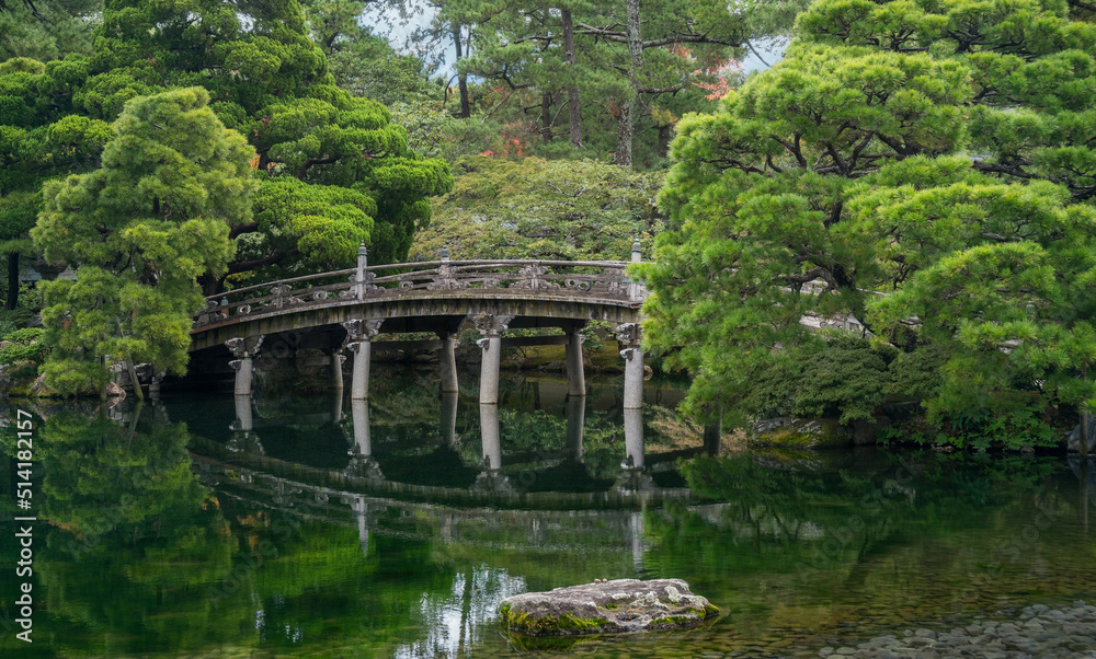 Historic stone bridge at Gonaitei garden on beautiful autumn day in Kyoto Imperial palace in Kyoto, Japan. Oike-niwa - serene japanese zen garden and pond