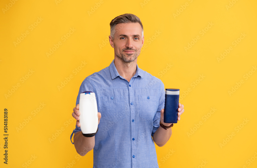 guy showing shampoo bottle on yellow background, skin guy showing shampoo bottle on yellow background, skin