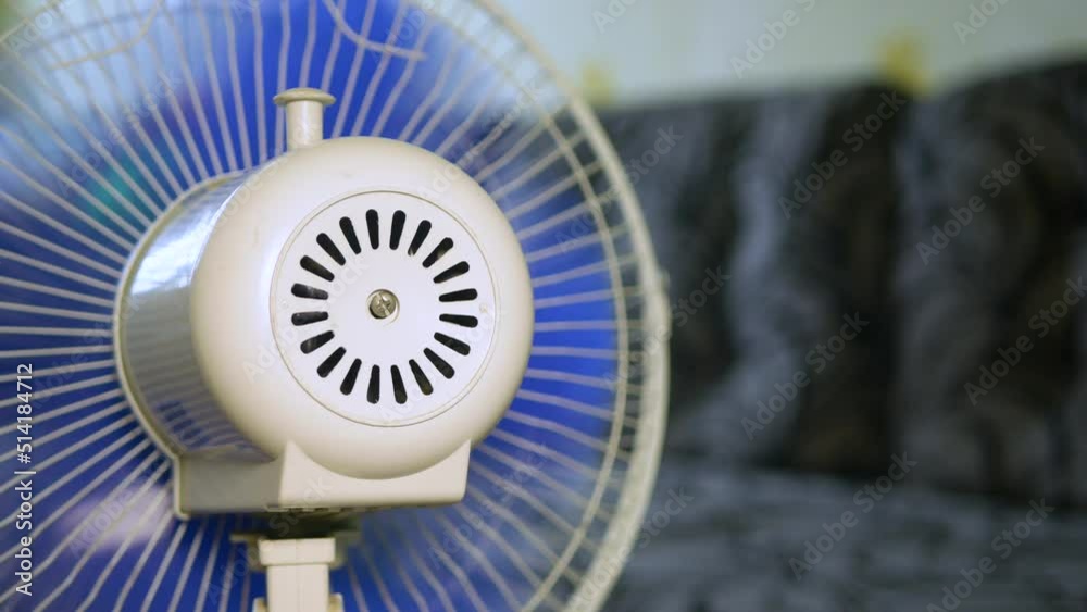 A fan with blue blades blows a room on a hot summer day A fan with blue blades blows a room on a hot summer day