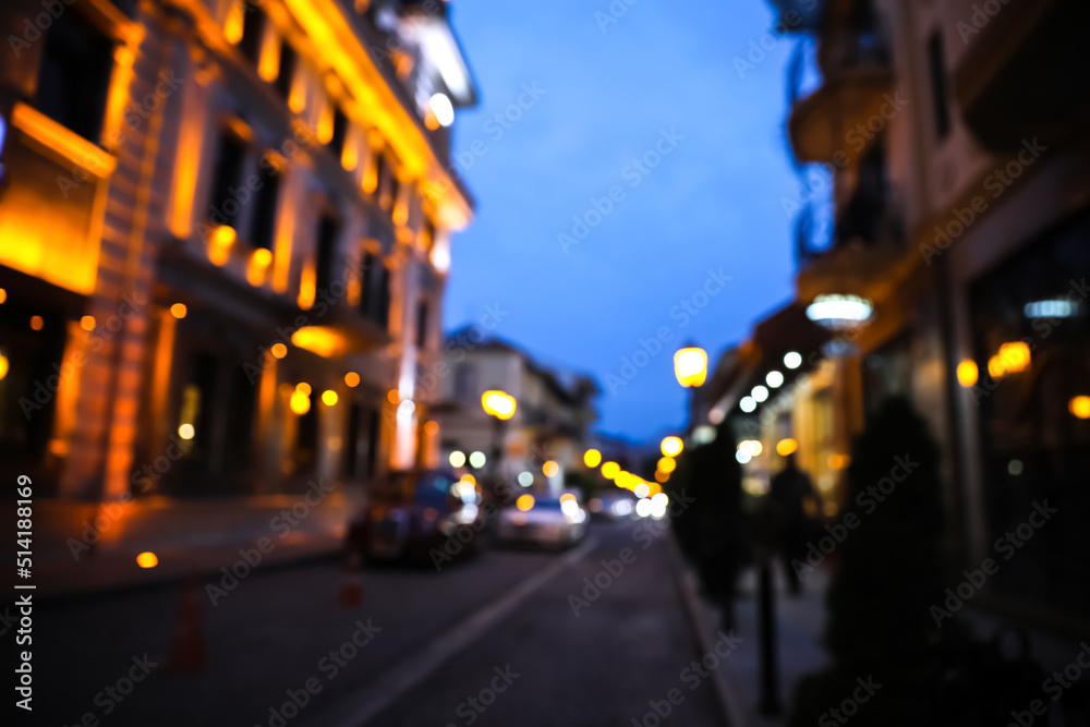 Blurred view of beautiful cityscape with glowing streetlights and illuminated building in evening