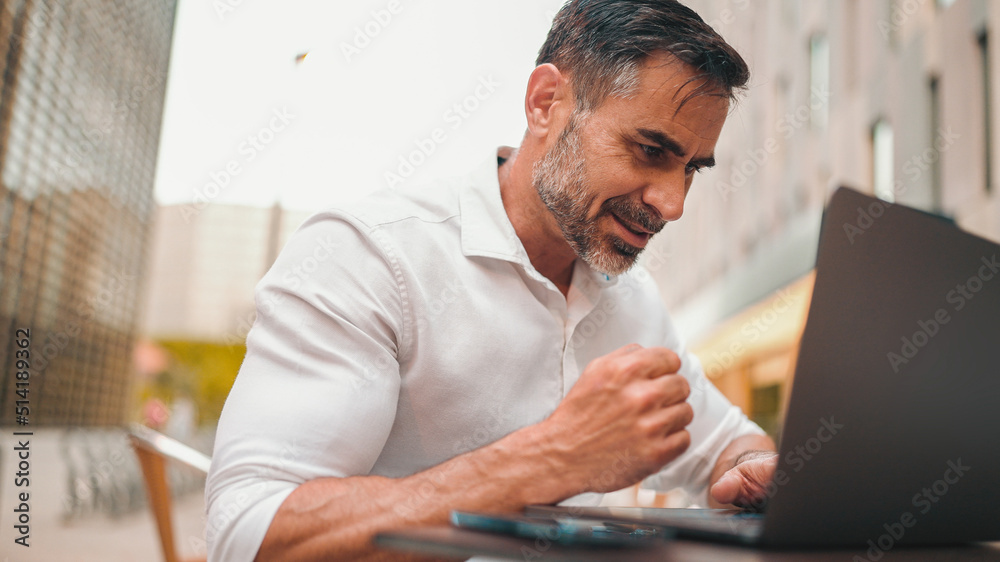 Mature businessman with neat beard wearing white shirt user on laptop pc computer sit at cafe outdoors. Successful man sitting at cafe table outdoors on nature Mobile office freelance Mature businessman with neat beard wearing white shirt user on laptop pc computer sit at cafe outdoors. Successful man sitting at cafe table outdoors on nature Mobile office freelance