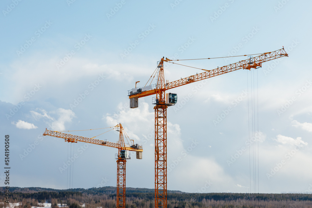 building cranes at the construction site on blue sky background building cranes at the construction site on blue sky background