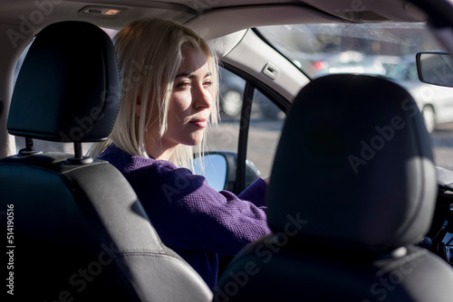 Happy cute Caucasian brunette driving her car . Photo taken from backseat. © 2Design