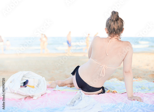 Young adult woman with a fit body wears a bikini with a thong while enjoying a day at the beach during summer vacations on the Mediterranean coast of Guardamar.