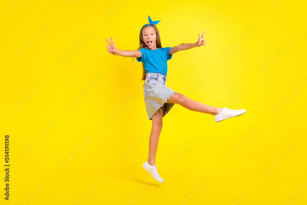 Full length portrait of excited friendly pupil jump hands fingers demonstrate v-sign isolated on yellow color background Full length portrait of excited friendly pupil jump hands fingers demonstrate v-sign isolated on yellow color background