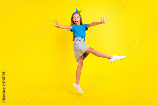 Full length portrait of excited friendly pupil jump hands fingers demonstrate v-sign isolated on yellow color background