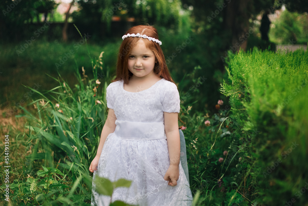 Portrait of shiny, positive and adorable redhead armenian girl standing in garden and looking at camera