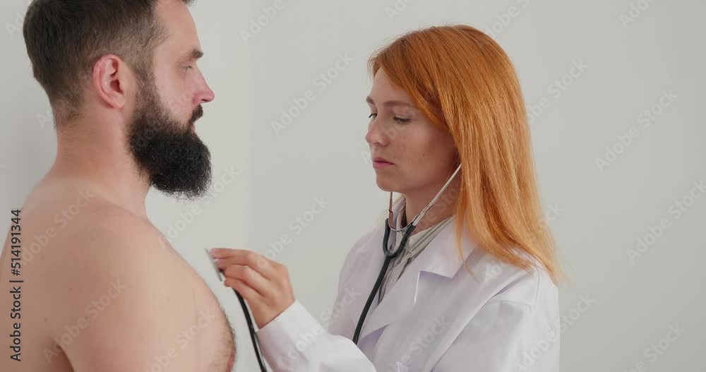 Woman doctor examines patient lungs with stethoscope in room. Medium shoot. Woman doctor examines patient lungs with stethoscope in room. Medium shoot.