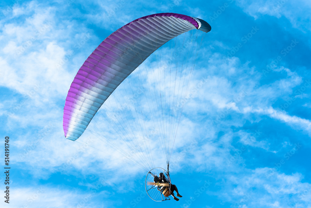 The people was playing a Paramotor which a small aircraft, flying on fresh blue sky and white clouds, Beautiful nature to recreation concept. The people was playing a Paramotor which a small aircraft, flying on fresh blue sky and white clouds, Beautiful nature to recreation concept.
