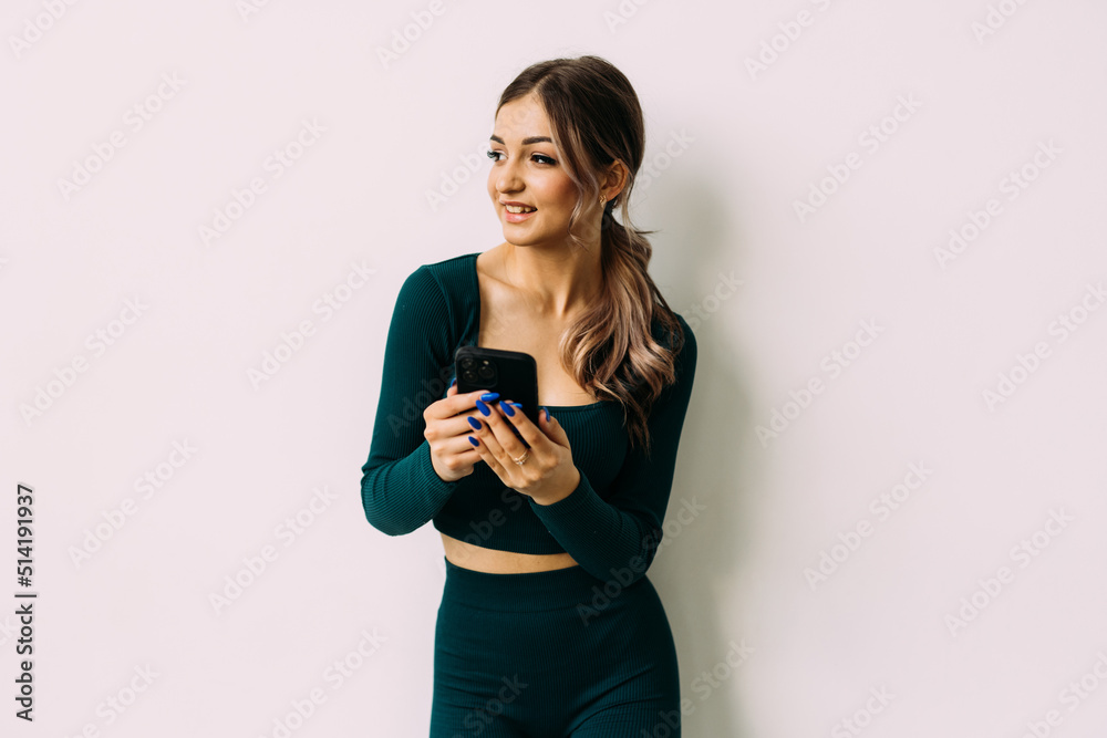Attractive young woman with a fitness mat using mobile phone at the yoga studio Attractive young woman with a fitness mat using mobile phone at the yoga studio