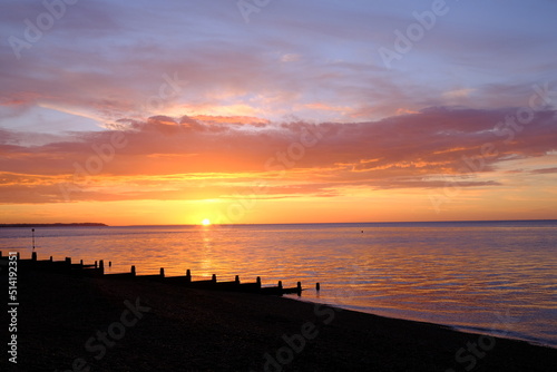 View of a beautifully colourful seaside sunset across a beach silhouette. photo