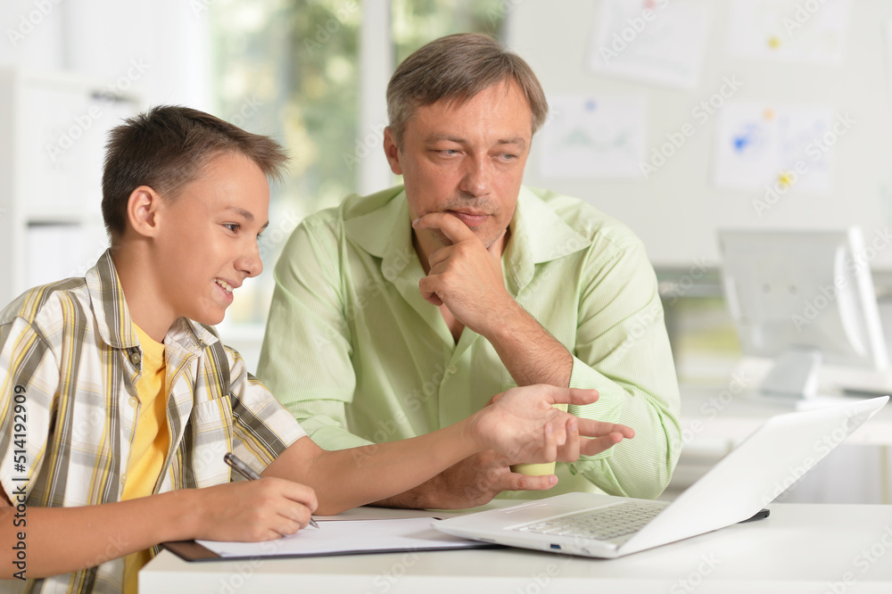 Portrait of son and father using laptop at home Portrait of son and father using laptop at home