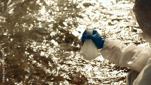 Ecologists sample water contaminated with dangerous, waterhazard toxins into tubes, Scientist or Biologist in protective waste water from industrial for analyze, problem environment, Testing toxic. photo