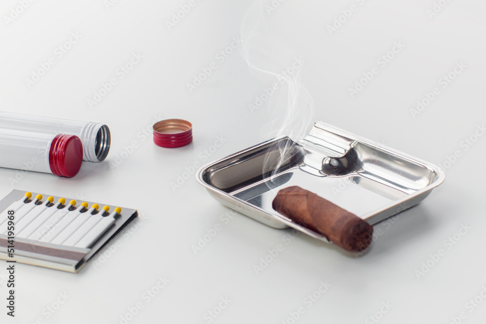 Ashtray with a smoldering cigar and an open box of matches, on an isolated white background Ashtray with a smoldering cigar and an open box of matches, on an isolated white background