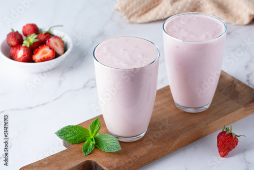Yogurt , buttermilk or kefir with strawberry. Yogurt in glass on light background. Probiotic cold fermented dairy drink. Gut health, fermented products, healthy gut flora concept photo